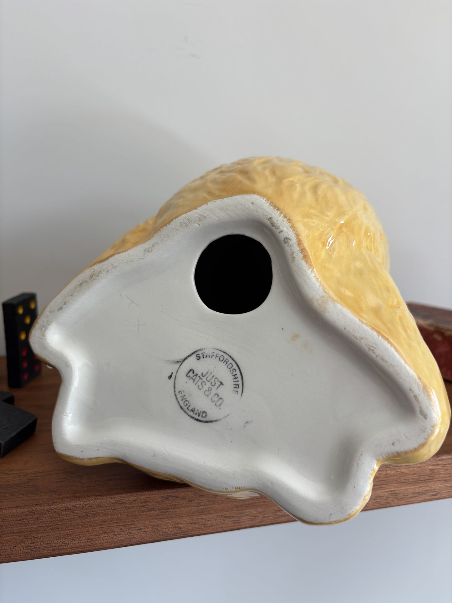 The base of a glossy ceramic teddy bear in an upside down pose showing Staffordshire, England, Just Cat's & Co makers mark.