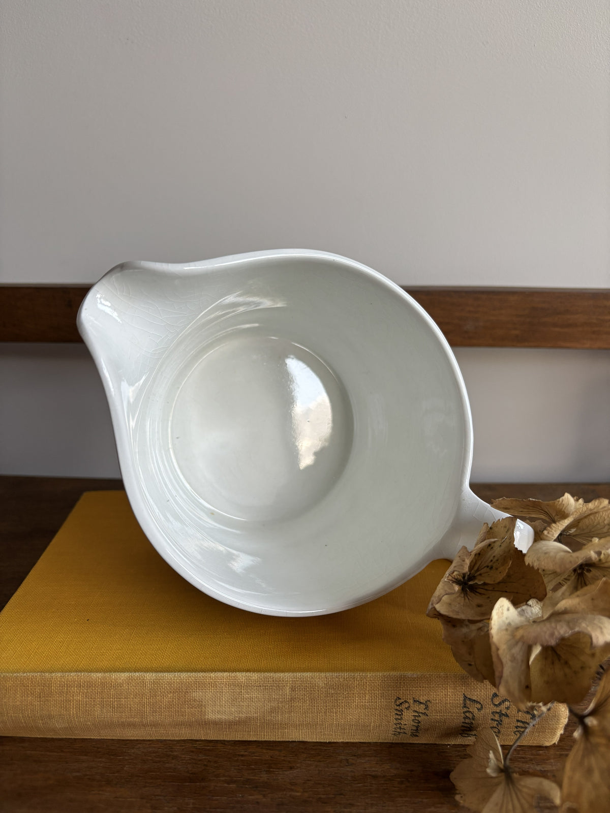 A vintage white sauce boat with a yellow floral display.