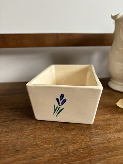 An off white ceramic vintage butter dish with a blue hand painted flower design