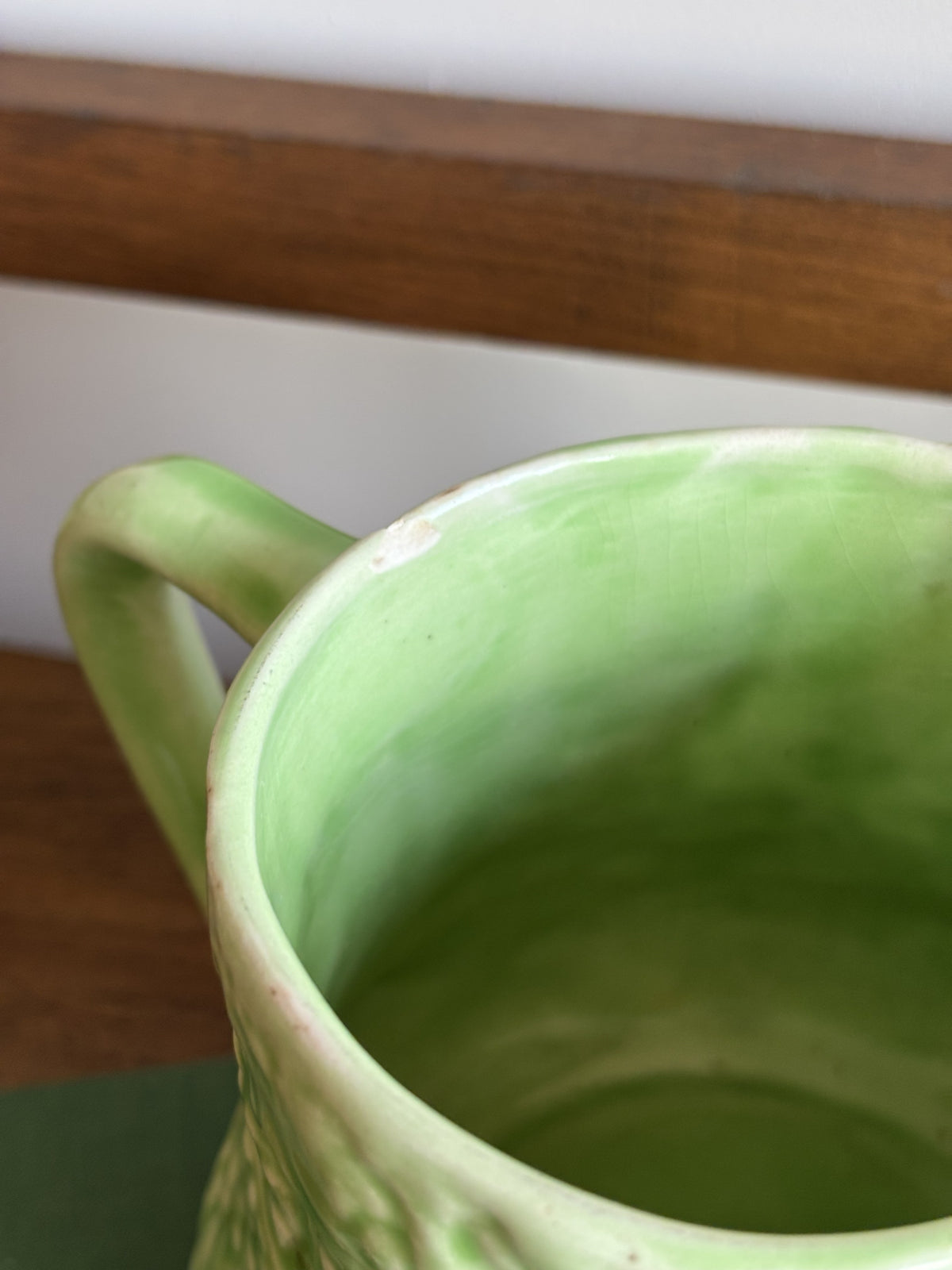 A close up of a chip on an English Majolica style green cabbage leaf textured jug.  
