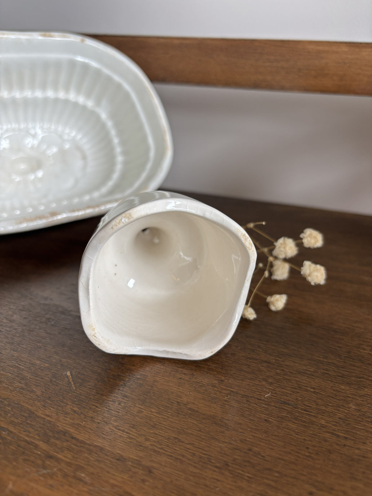 The inside of a white ceramic pie funnel on a dark wooden surface, with a matching white ceramic tray partially visible in the background.
