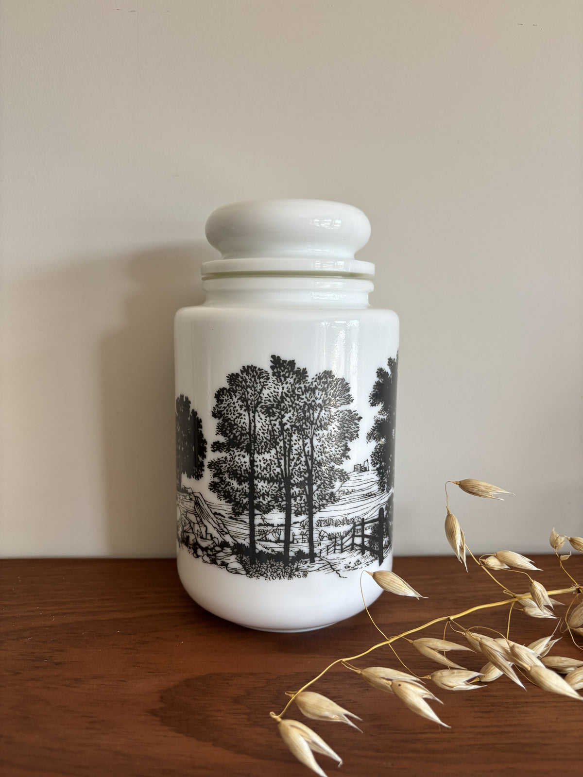 A opaline milk glass storage jar with a black transferware countryside scene.  