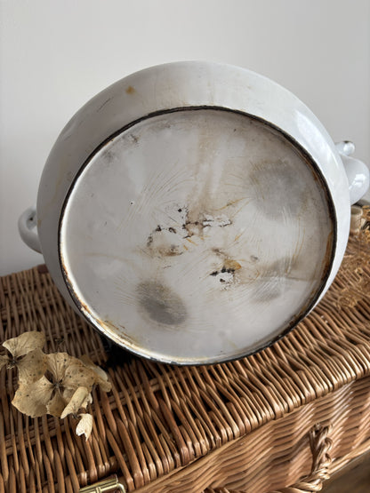 The bottom of a white enamel teapot showing considerable signs of wear.  