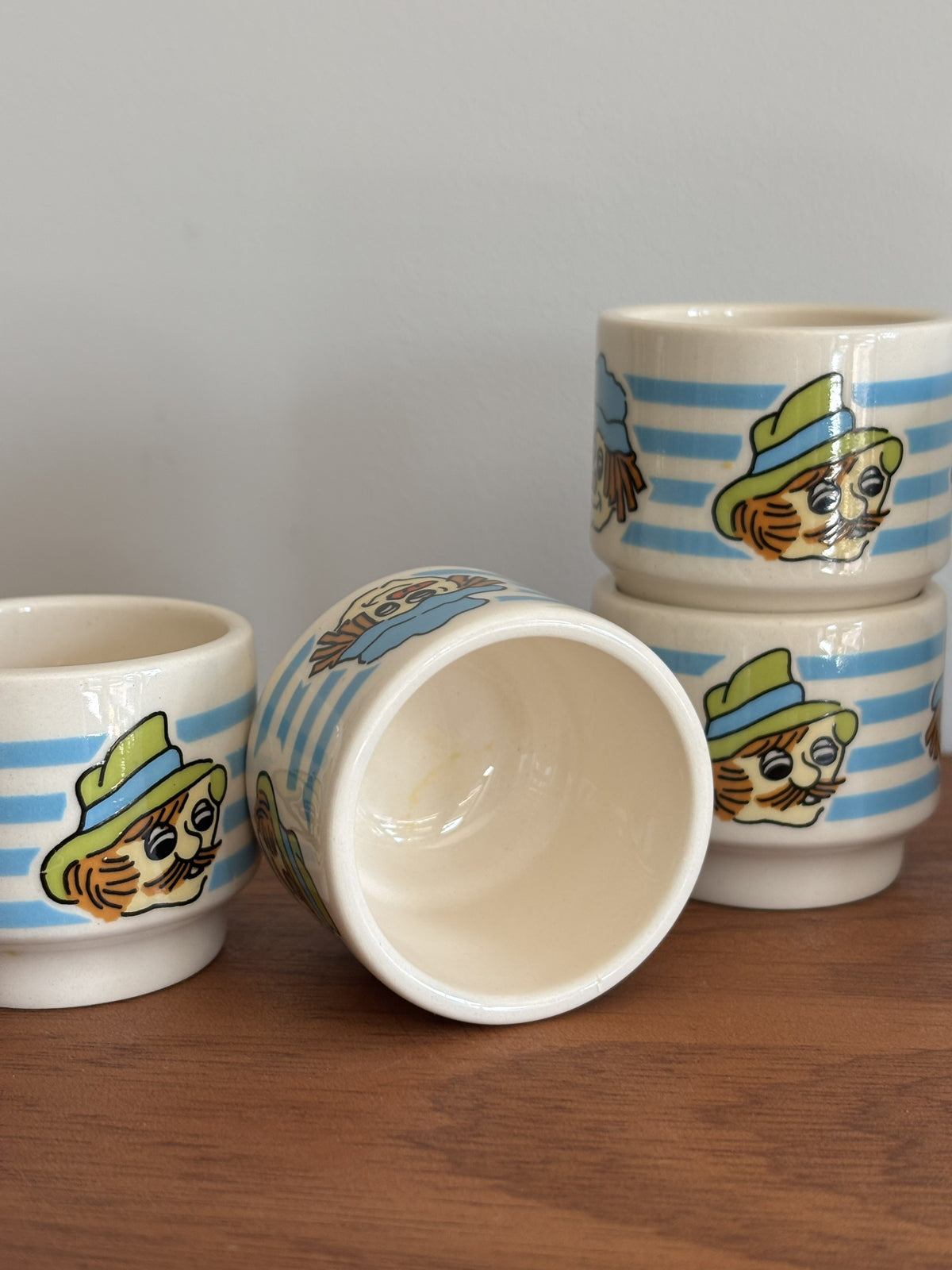 Six small Vintage Hornsea ceramic cups with blue and white stripes and whimsical faces wearing hats. 