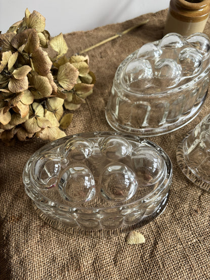 Clear glass jelly mould on a textured fabric surface with dried flowers.