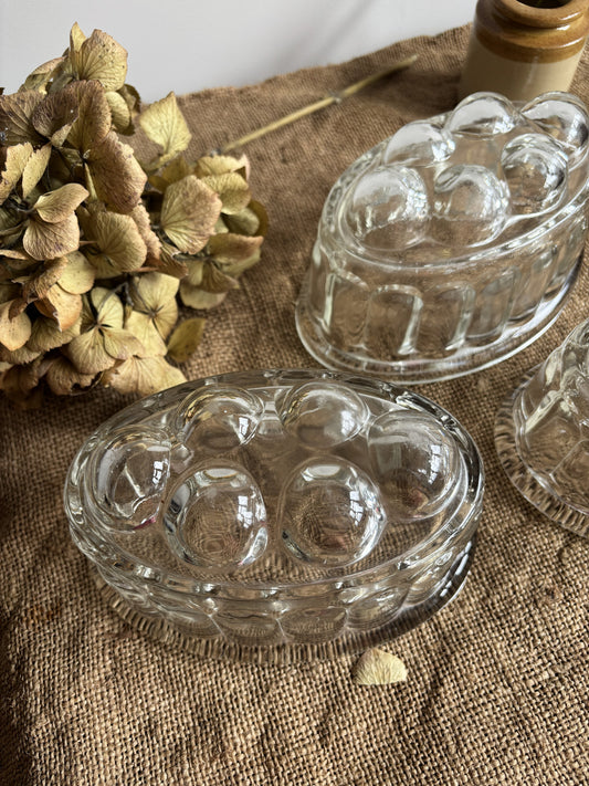 Clear glass jelly mould on a textured fabric surface with dried flowers.