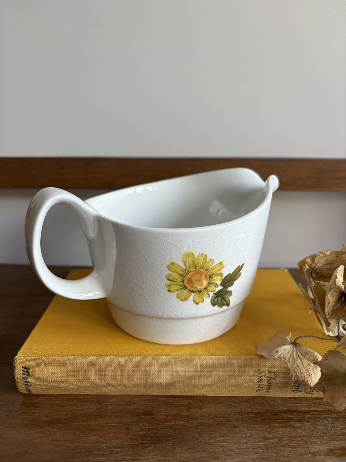 A vintage white sauce boat with a yellow floral display.  