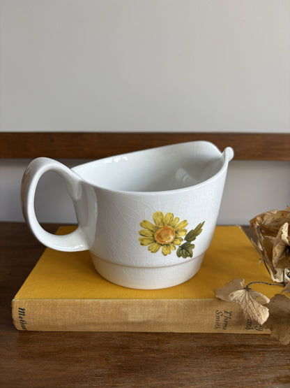 A vintage white sauce boat with a yellow floral display.  