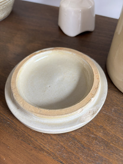 A close-up of a white ceramic lid with a chip resting on a dark wooden surface.