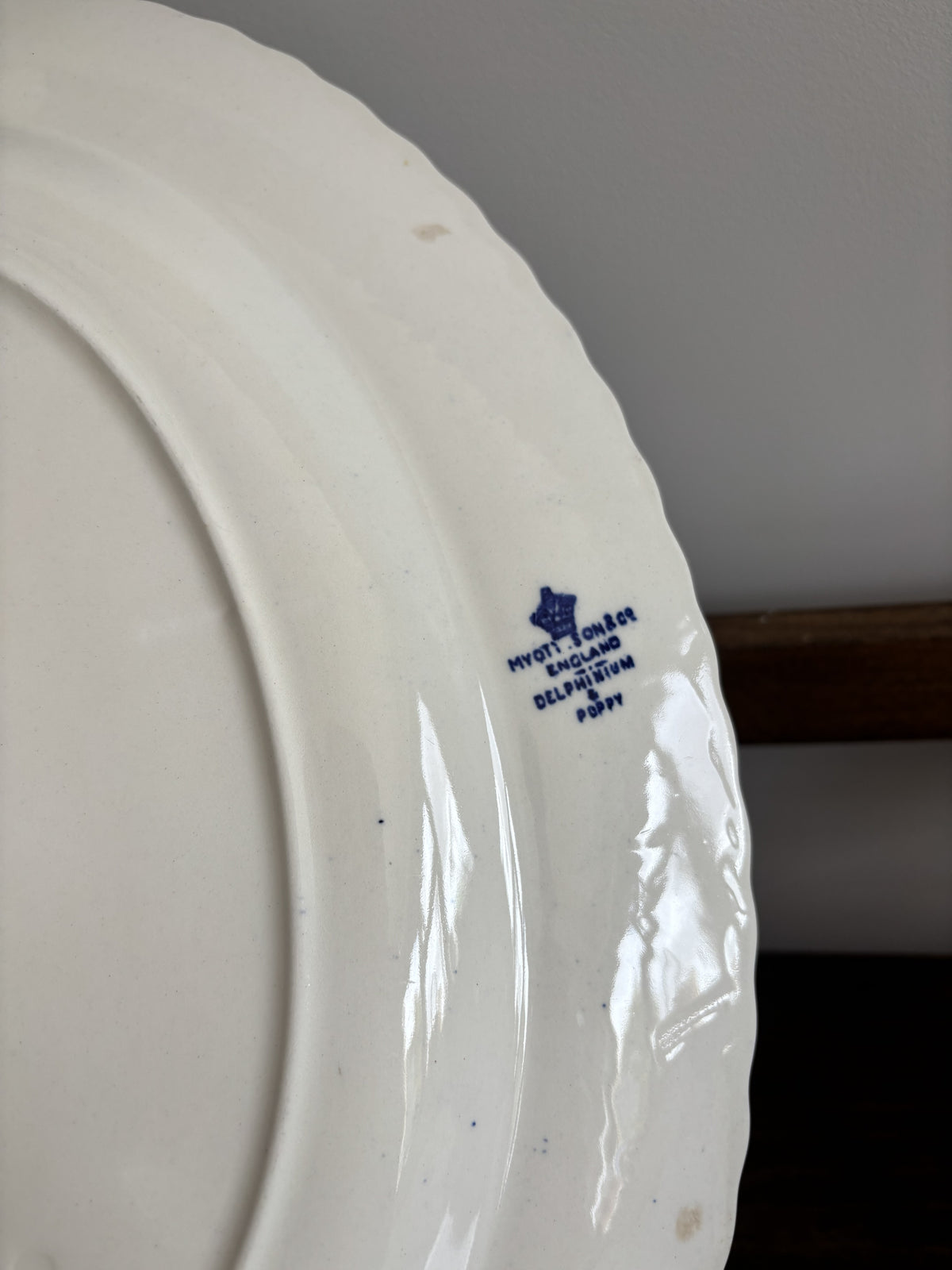 Close-up of a white ceramic plate showing the blue printed 'Myott Sons Co England Delphinium & Poppy' words