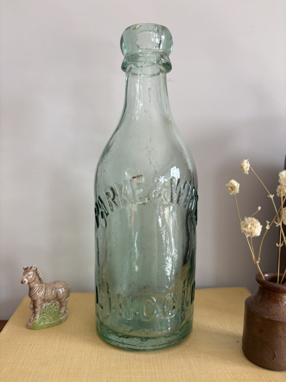 A vintage aqua green Parke & White glass bottle with embossed lettering sitting on top of a yellow book.  