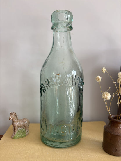 A vintage aqua green Parke & White glass bottle with embossed lettering sitting on top of a yellow book.  