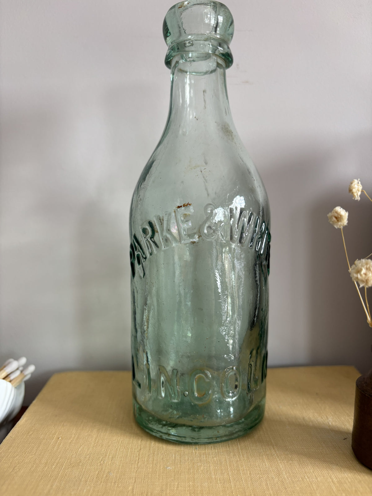 A vintage aqua green Parke & White glass bottle with embossed lettering sitting on top of a yellow book.  