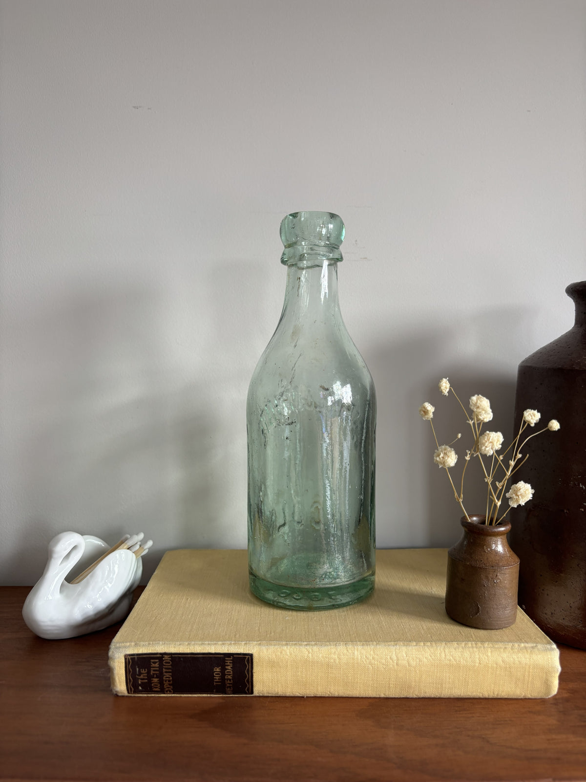 A vintage aqua green Parke & White glass bottle with embossed lettering sitting on top of a yellow book.  