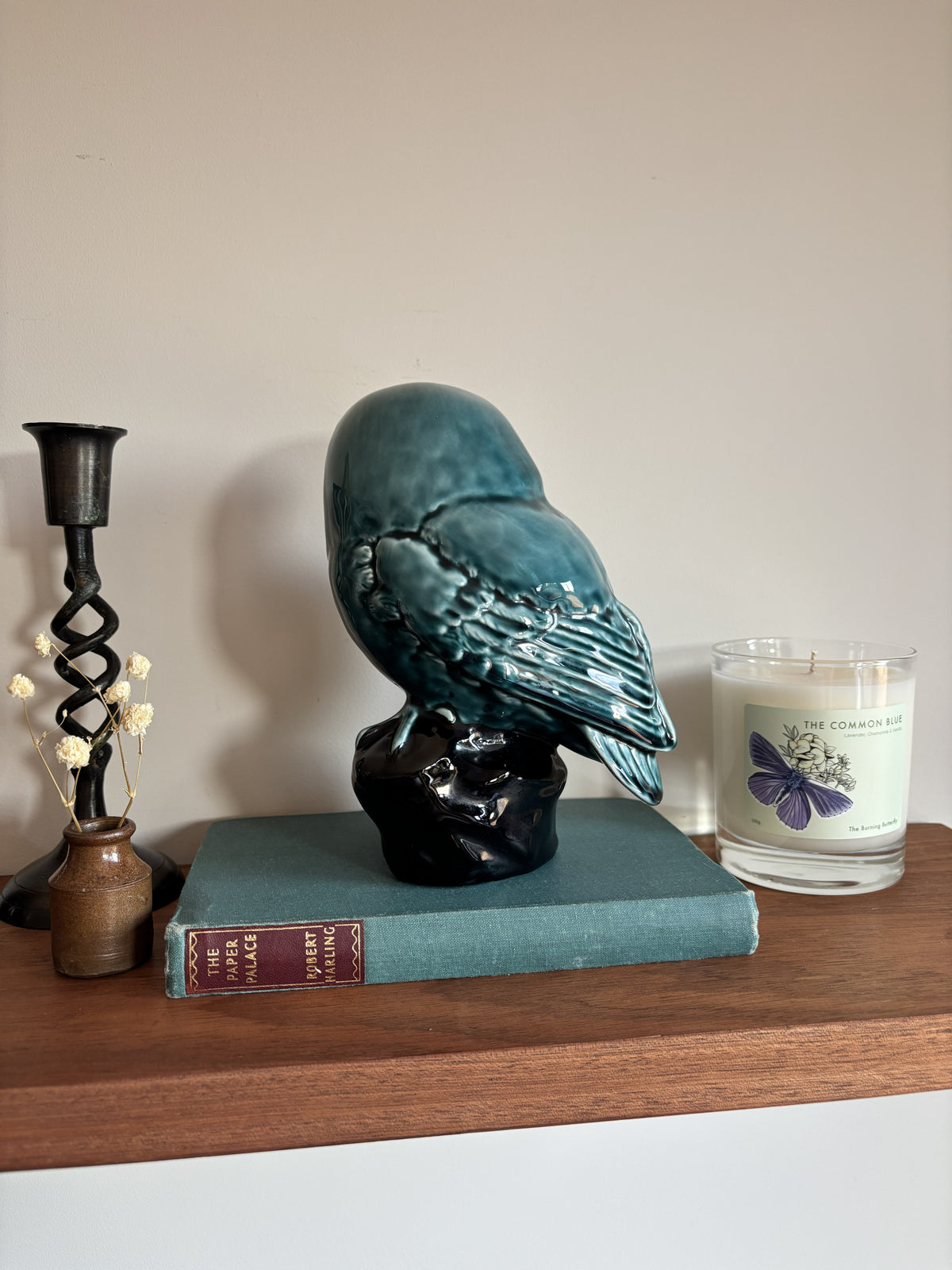 The back of a vintage Poole Pottery glossy teal-blue ceramic owl figurine perched on a dark base.