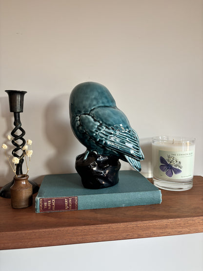 The back of a vintage Poole Pottery glossy teal-blue ceramic owl figurine perched on a dark base.