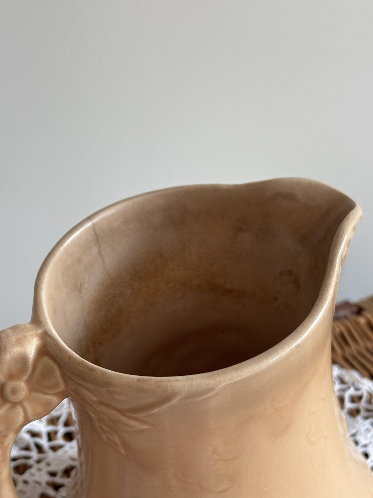 Vintage Price Bros art deco style beige jug with a cottage and floral 3D mould.  Close up of hairline crack in rim. 