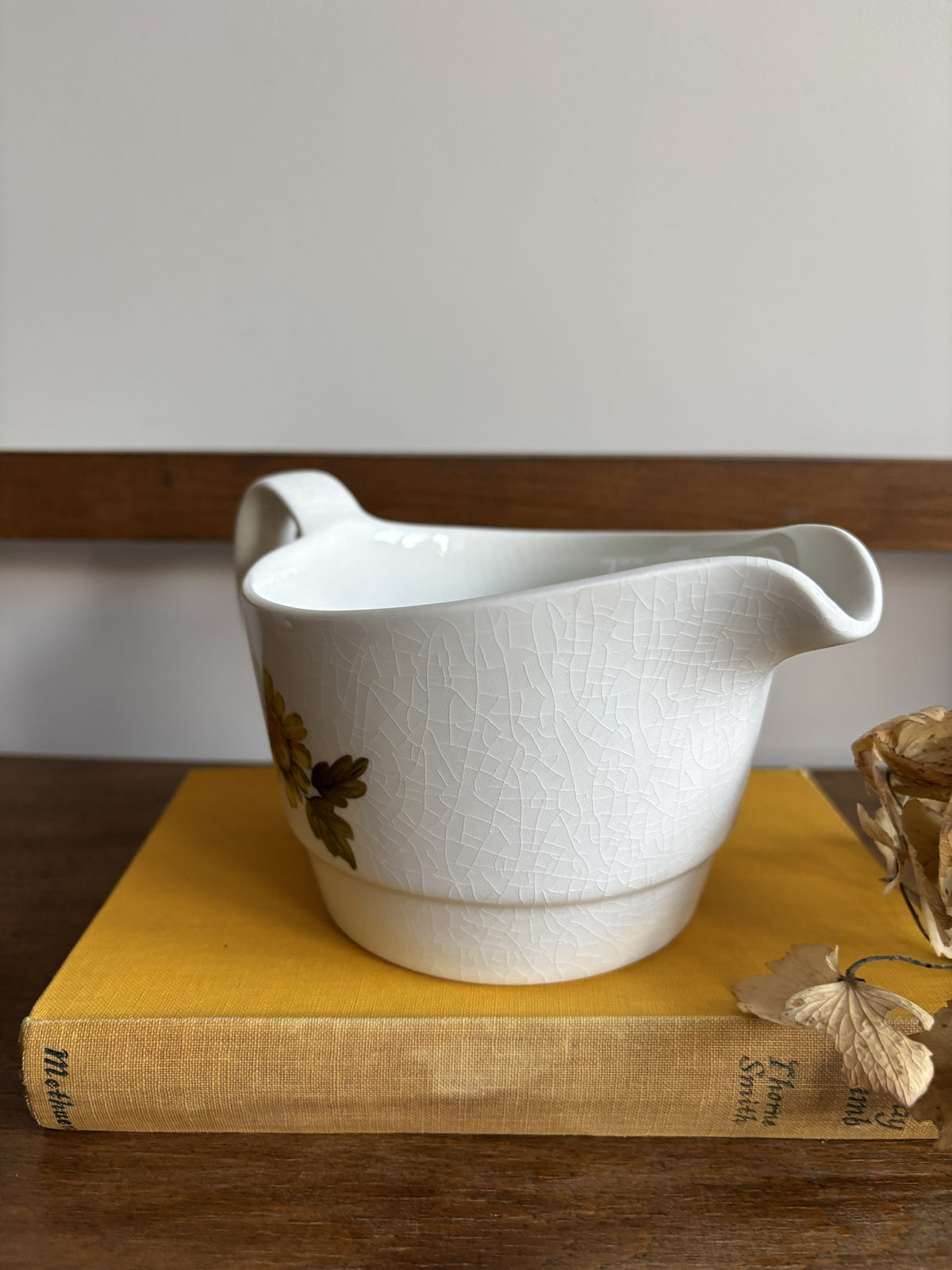 A vintage white sauce boat with a yellow floral display.  