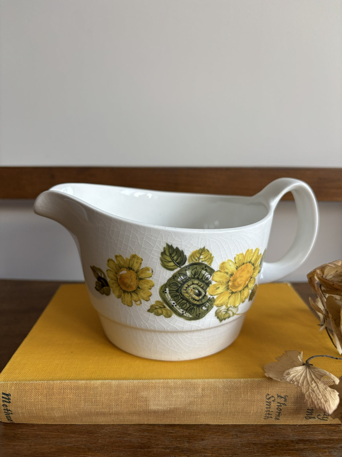 A vintage white sauce boat with a yellow floral display.  