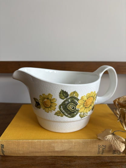 A vintage white sauce boat with a yellow floral display.  
