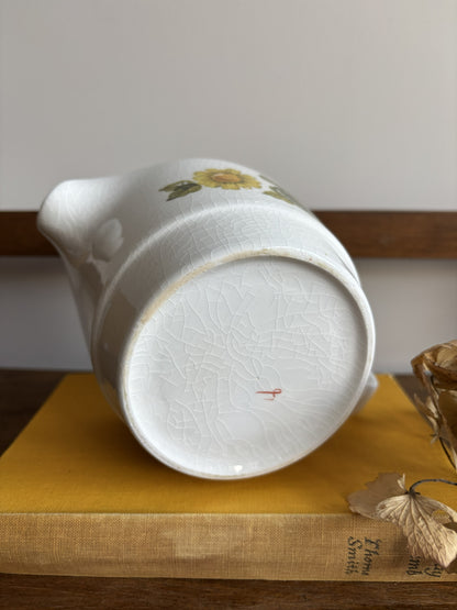 A vintage white sauce boat with a yellow floral display.  
