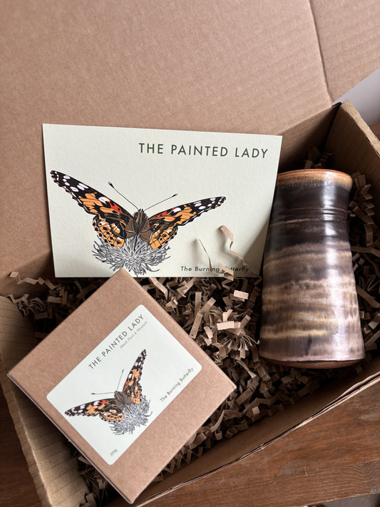 A gift box from The Burning Butterfly containing The Painted Lady candle in a kraft gift box, a small brown bud vase and The Painted Lady butterfly A6 postcard. 