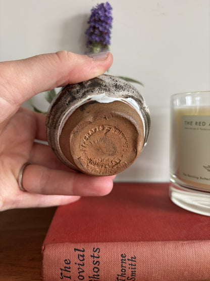 The base of a brown and white bud vase with a partial makers mark. 