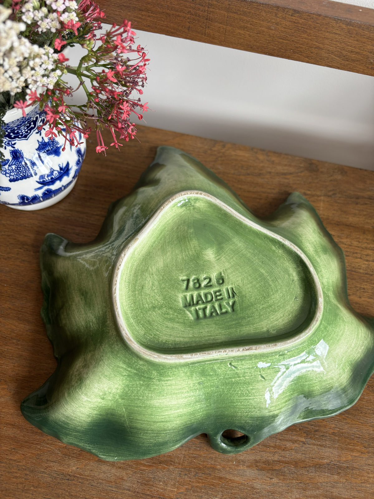 The base of a green Vietri Foglia Majolica Style Leaf bowl with the words Made in Italy and 7826 stamped on the bottom. 