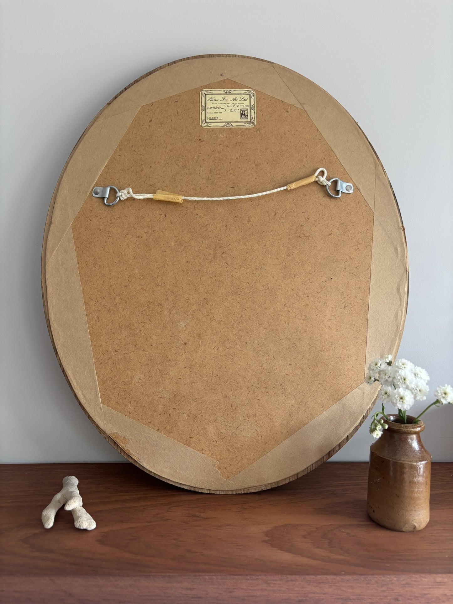 Round wooden picture frame on a wooden surface with a vase and flowers in the background.
